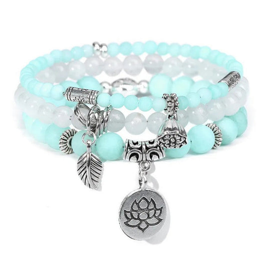 Stack of aqua beaded bracelets with silver charms on a white background