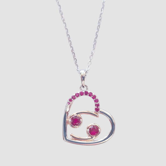 Heart-shaped pendant with zodiac cancer glyph with red gemstones on a chain against a neutral background