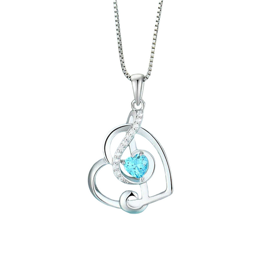 Silver necklace with a heart-shaped pendant featuring a blue gemstone on a light blue background with seashells.