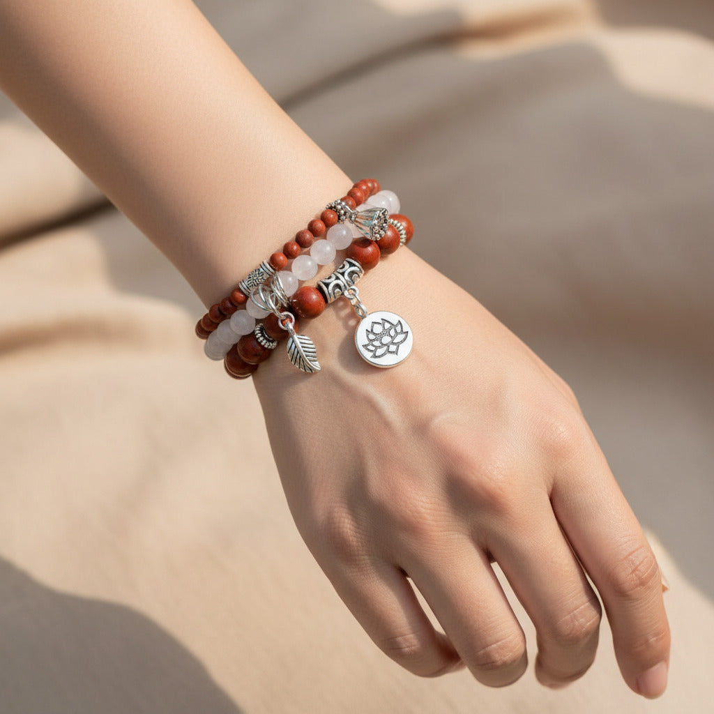 Stack of red and white beaded bracelets with silver charms on a white background