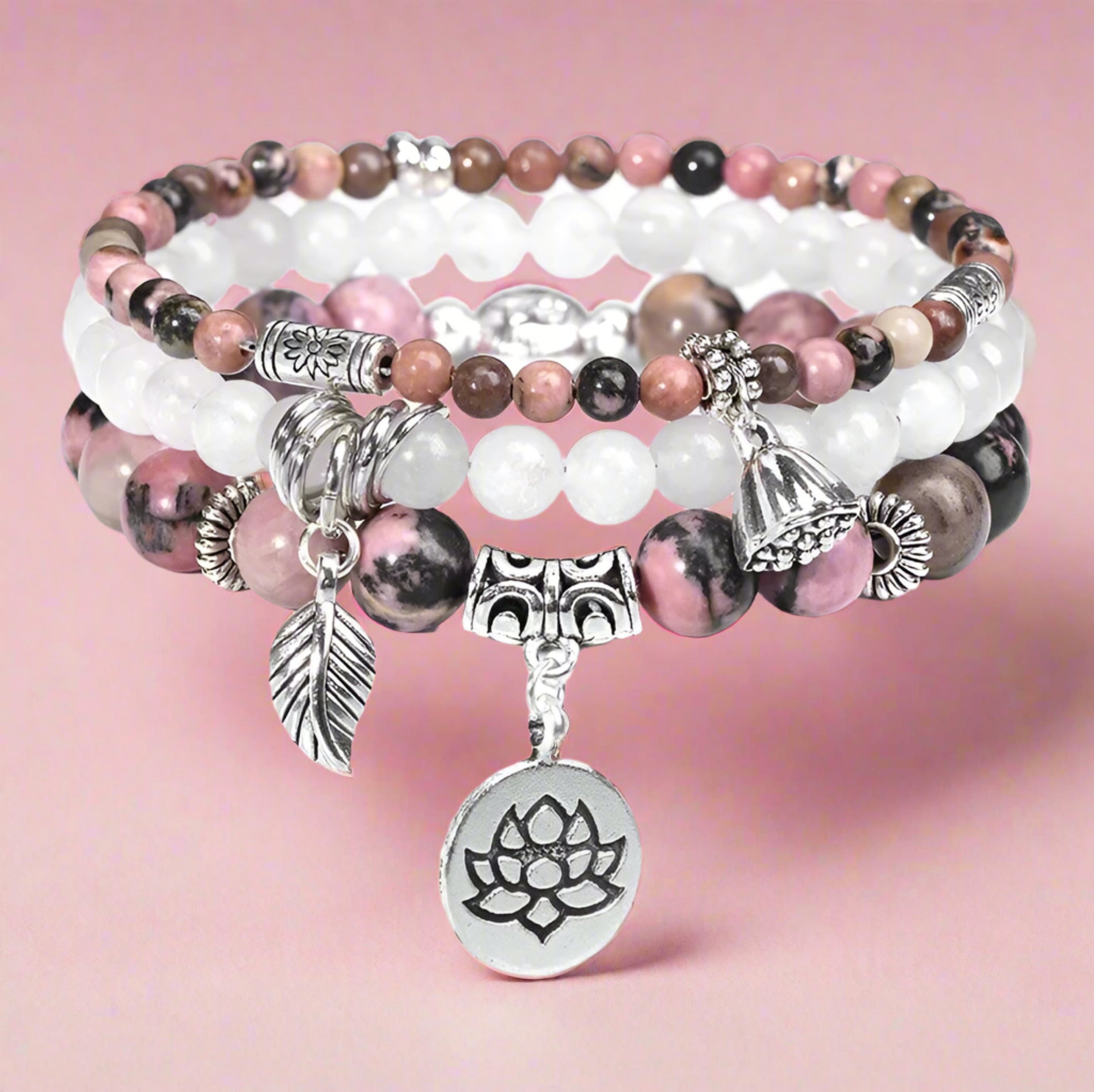 Stack of beaded bracelets with charms on a white background