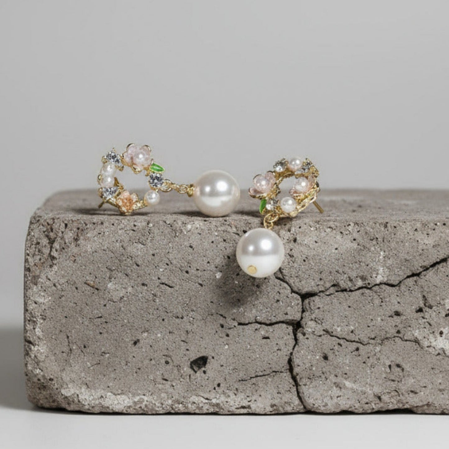Pair of pearl earrings on a concrete surface with a neutral background
