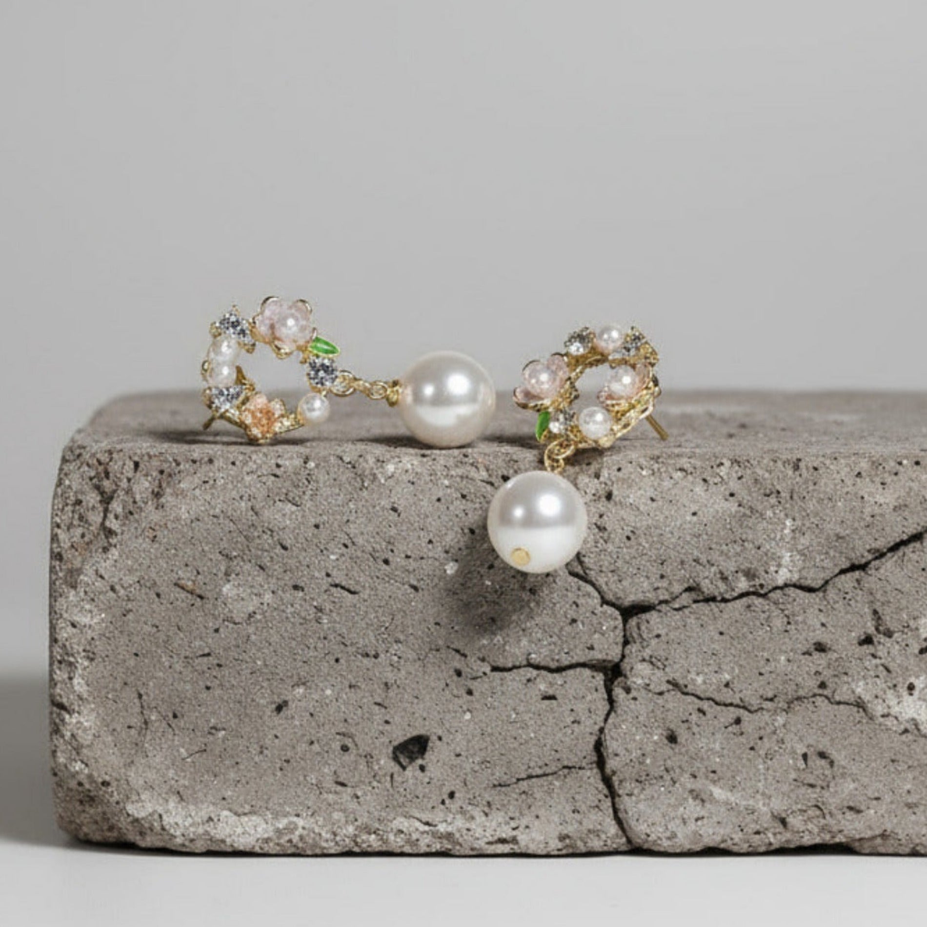 Pair of pearl earrings on a concrete surface with a neutral background