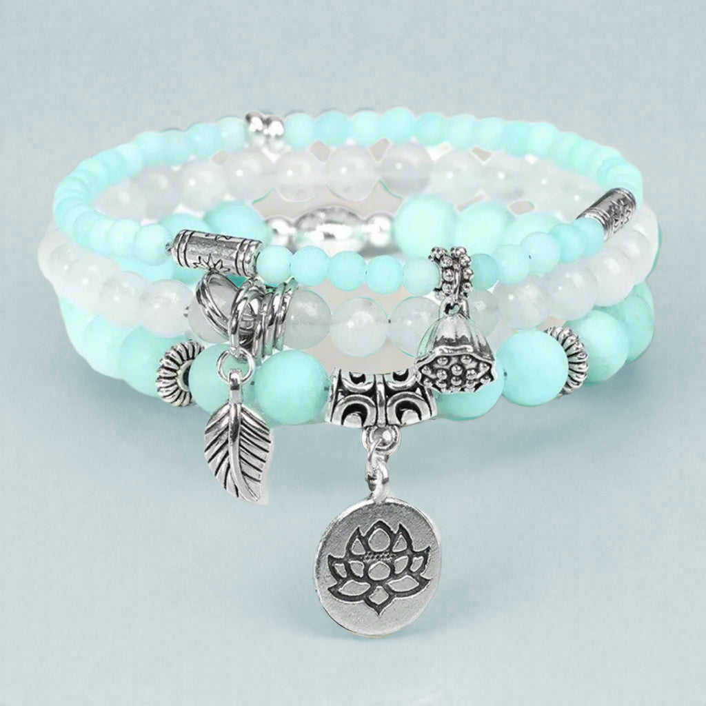 Turquoise beaded bracelet with silver charms on a light gray background
