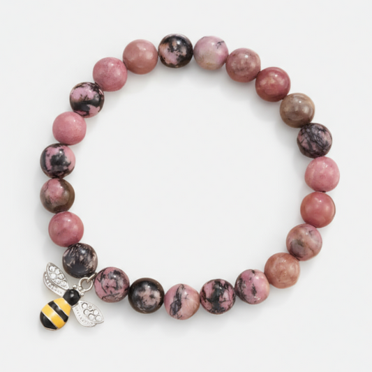 Bracelet with pink and brown beads and a bee charm on a white background