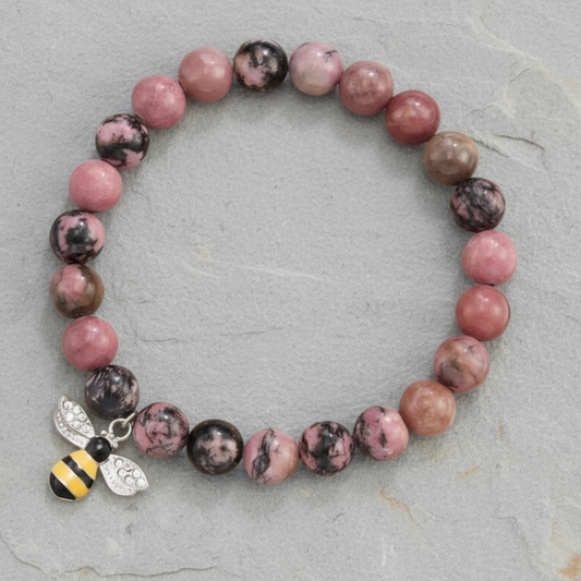 Bracelet with pink and brown beads and a bee charm on a white background