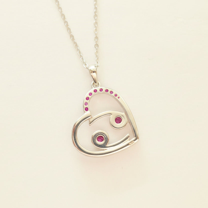Heart-shaped pendant with pink gemstones on a white background