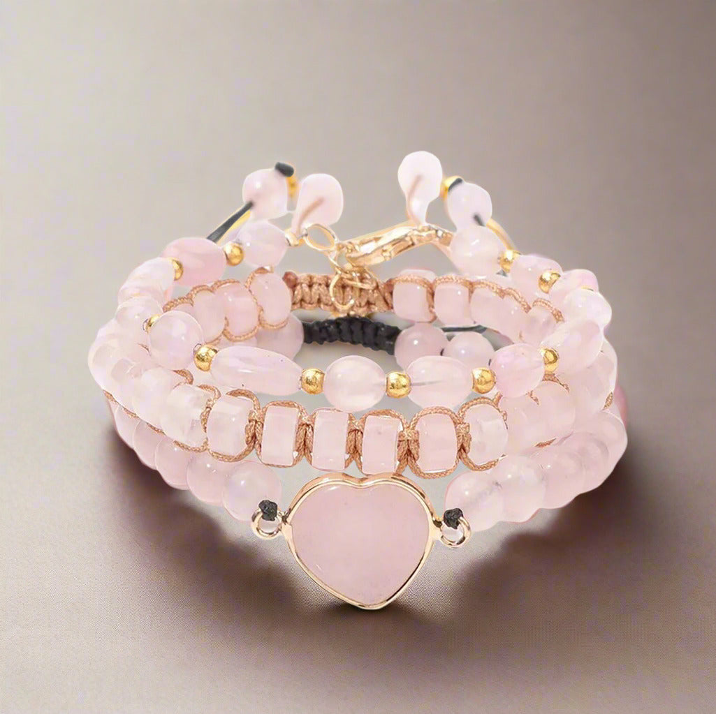 Set of pink beaded bracelets with a heart charm on a white background