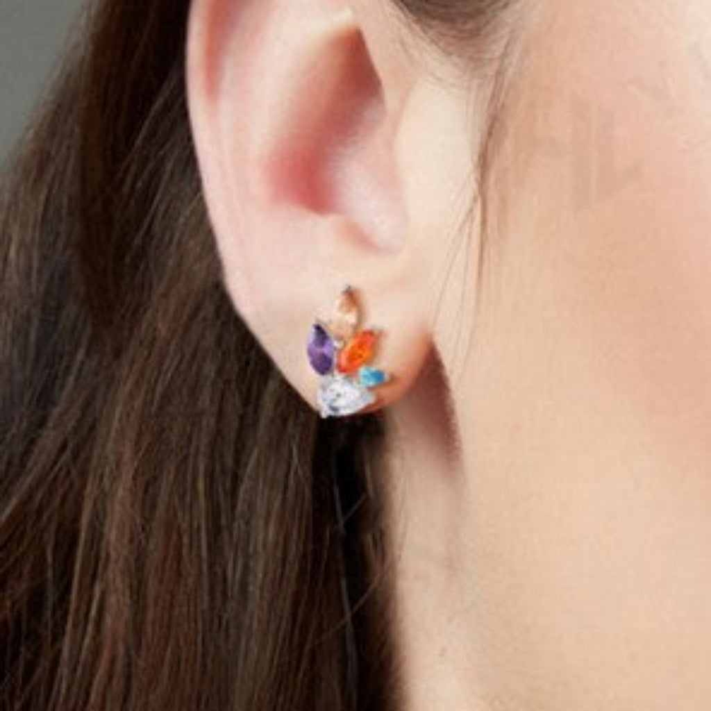 Close-up of a person wearing colorful earrings with a neutral background