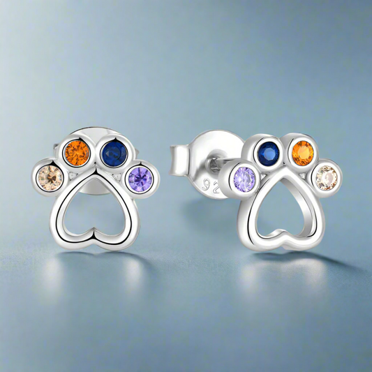 Silver paw-shaped earrings with colorful gemstones on a light blue background